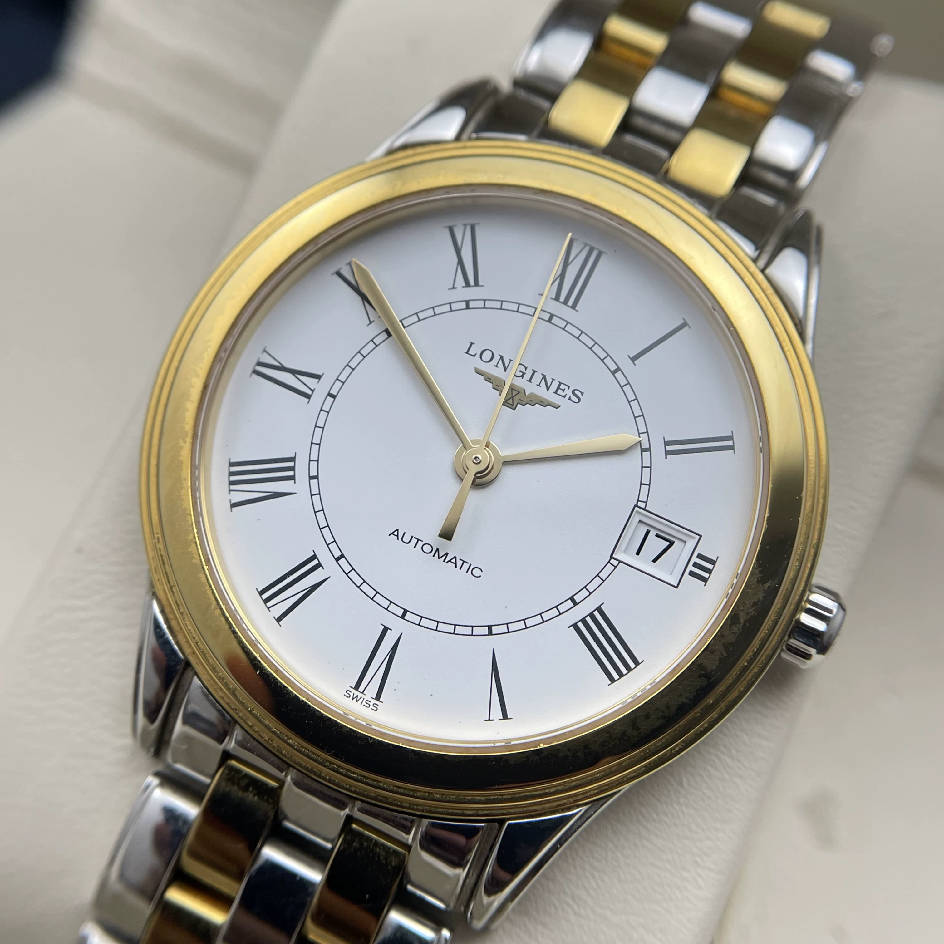 Detalhe do mostrador branco com numerais romanos e acabamento PVD dourado do Longines Flagship