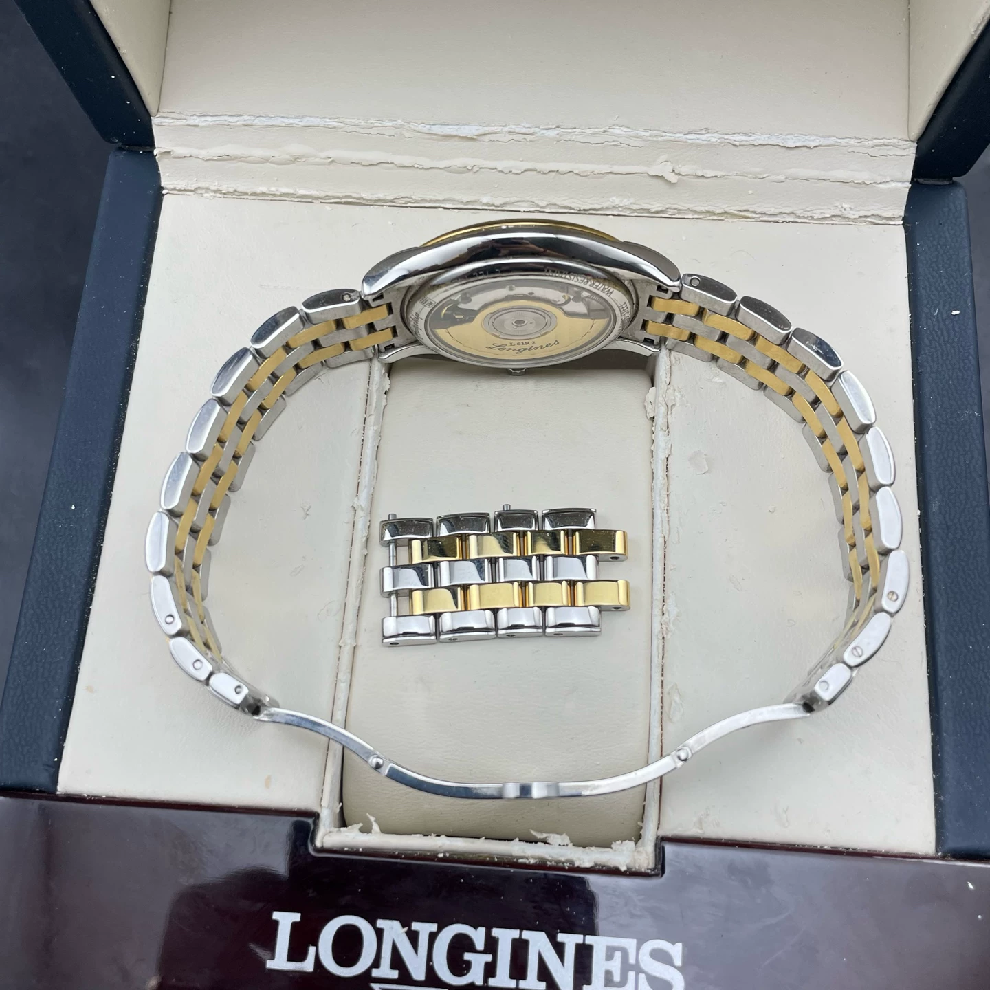 Longines Flagship com todos os elos extras da pulseira ao lado do fundo transparente